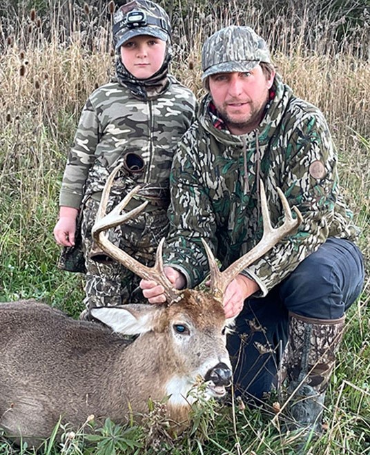 Father and son holding the horns of hunted buck